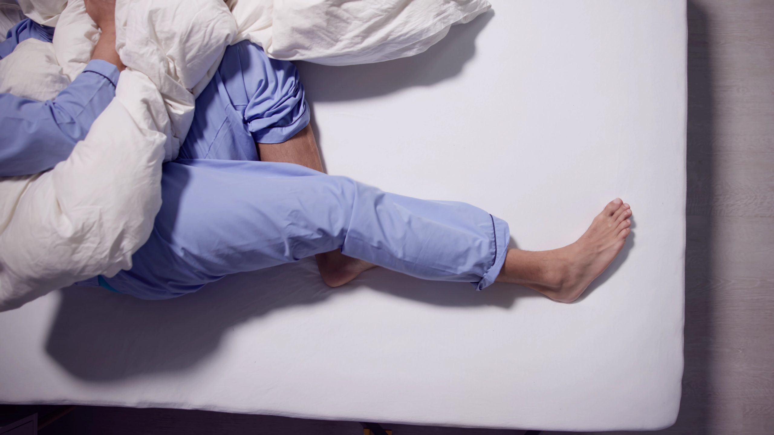 Man trying to sleep with restless leg syndrome (RLS)